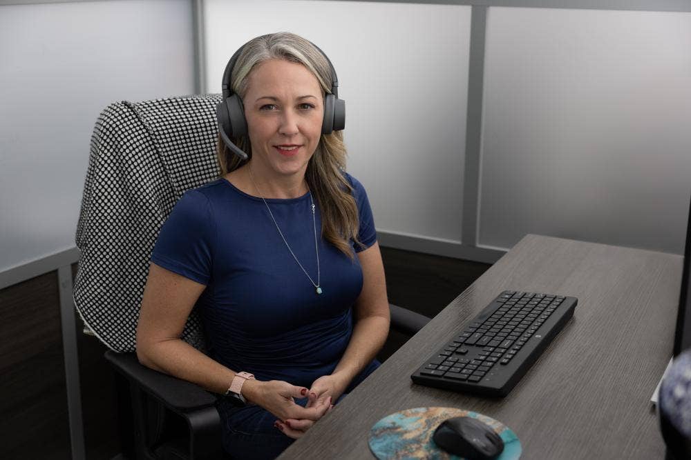 Lab Alley employee with headset sitting in front of computer and smiling at camera